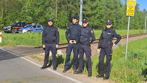 Przy przejeździe kolejowym stoją 3 umundurowanych funkcjonariuszu policji i Sok i umundurowana policjantka.
