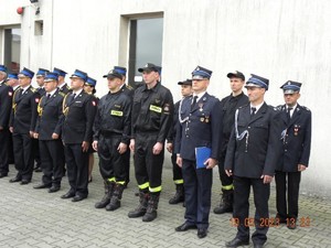 Grupa umundurowanych strażaków stojących w dwuszeregu.